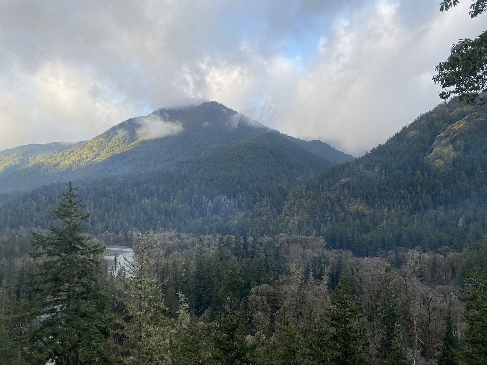 Olympic Peninsula mountain valley with clouds, river, and forested slopes — the landscape where Boots on the Ground works